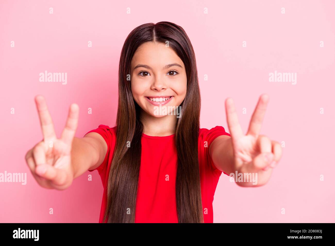 Foto di ragazza kid latino affascinante fare V-segno indossare rosso t-shirt isolata su sfondo rosa Foto Stock