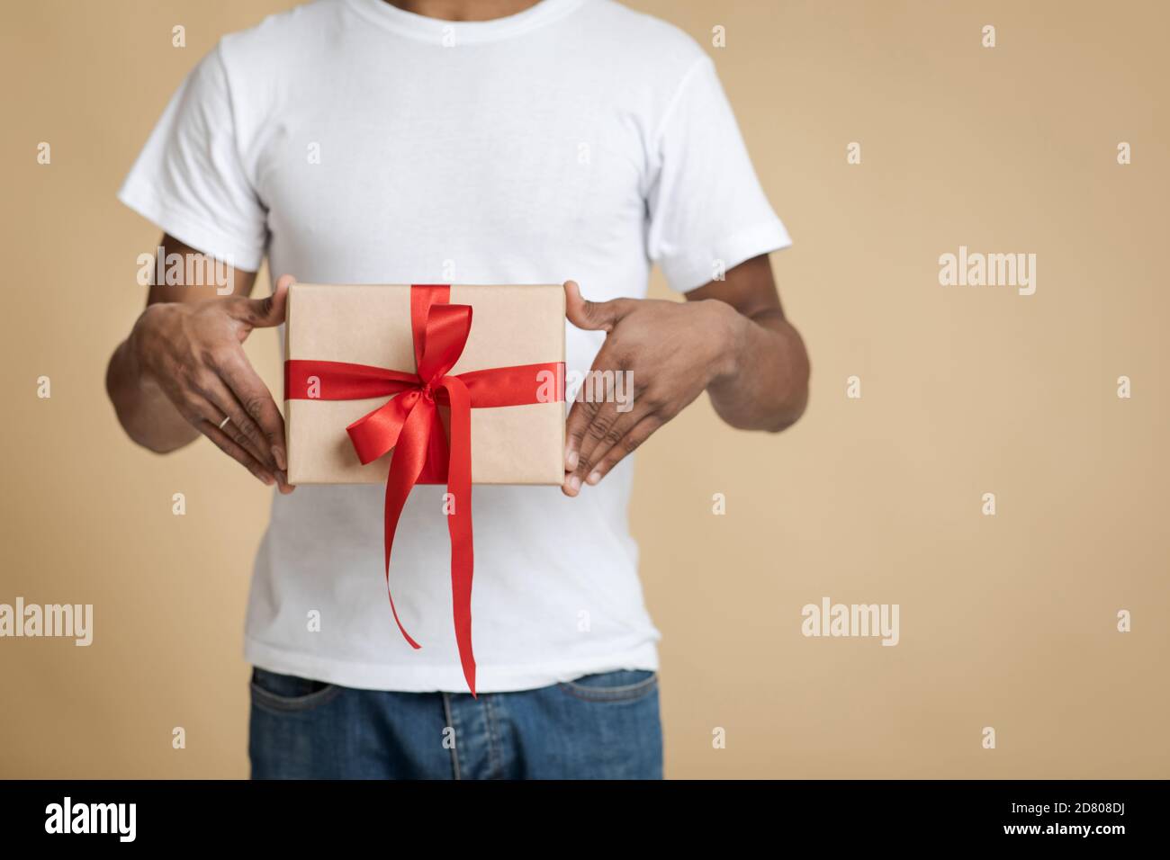Sorpresa per Natale e festa di famiglia. Uomo afroamericano in scatola da T-shirt bianca con regalo Foto Stock