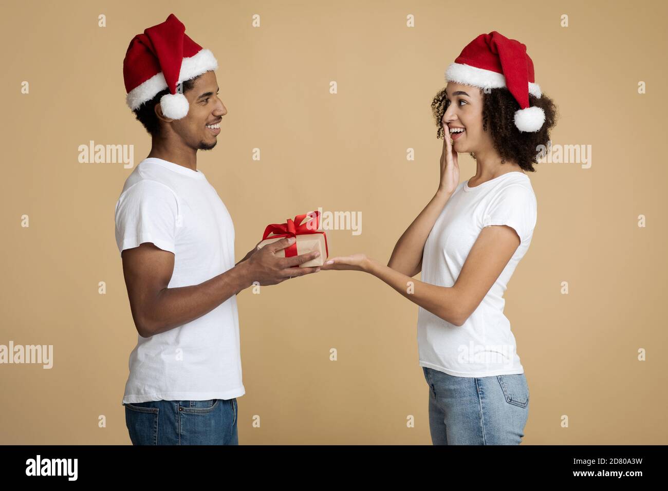 Giovane bell'uomo afro-americano bearded dà alla donna Natale presente Foto Stock