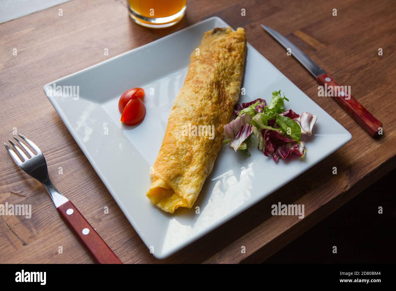 uova fritte con pomodoro e lattuga in un quadrato bianco piatto su un tavolo di servizio Foto Stock