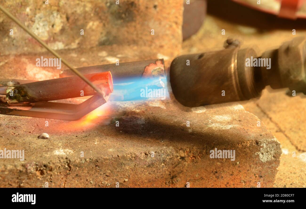 Un articolo in ottone viene saldato in argento con una torcia a gas. Foto Stock