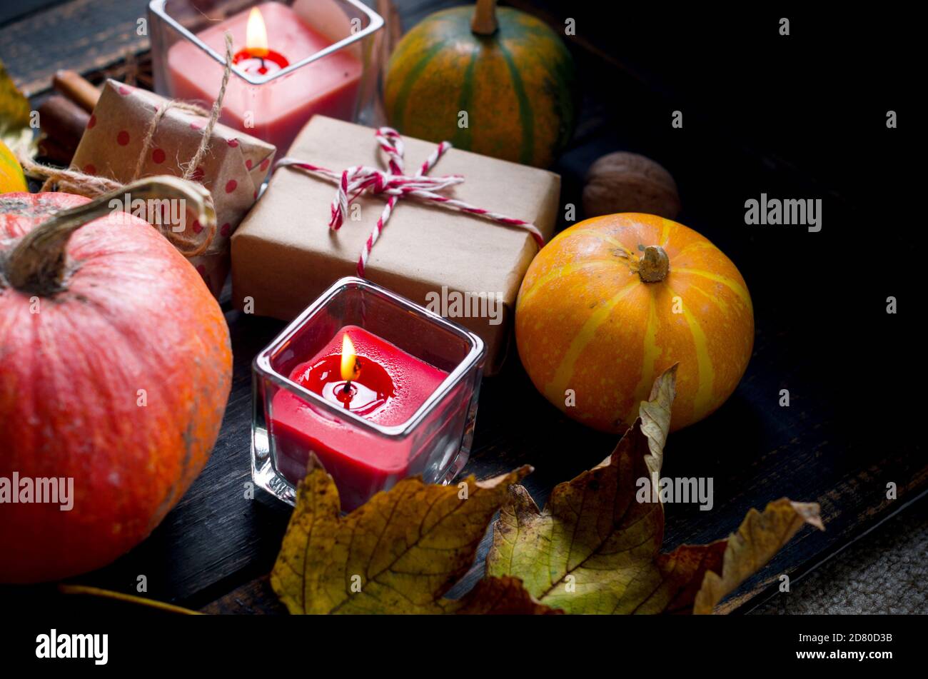 composizione autunnale con candele, zucche e foglie autunnali, tazza di tè su tavola di legno. Foto Stock