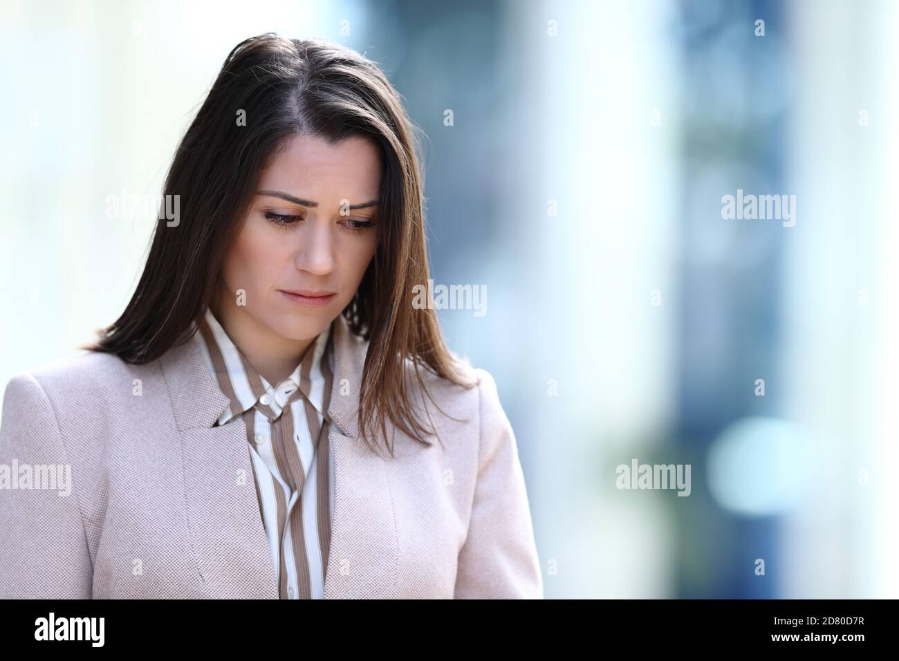 Triste donna che si lamenta di camminare per strada guardando giù Foto Stock