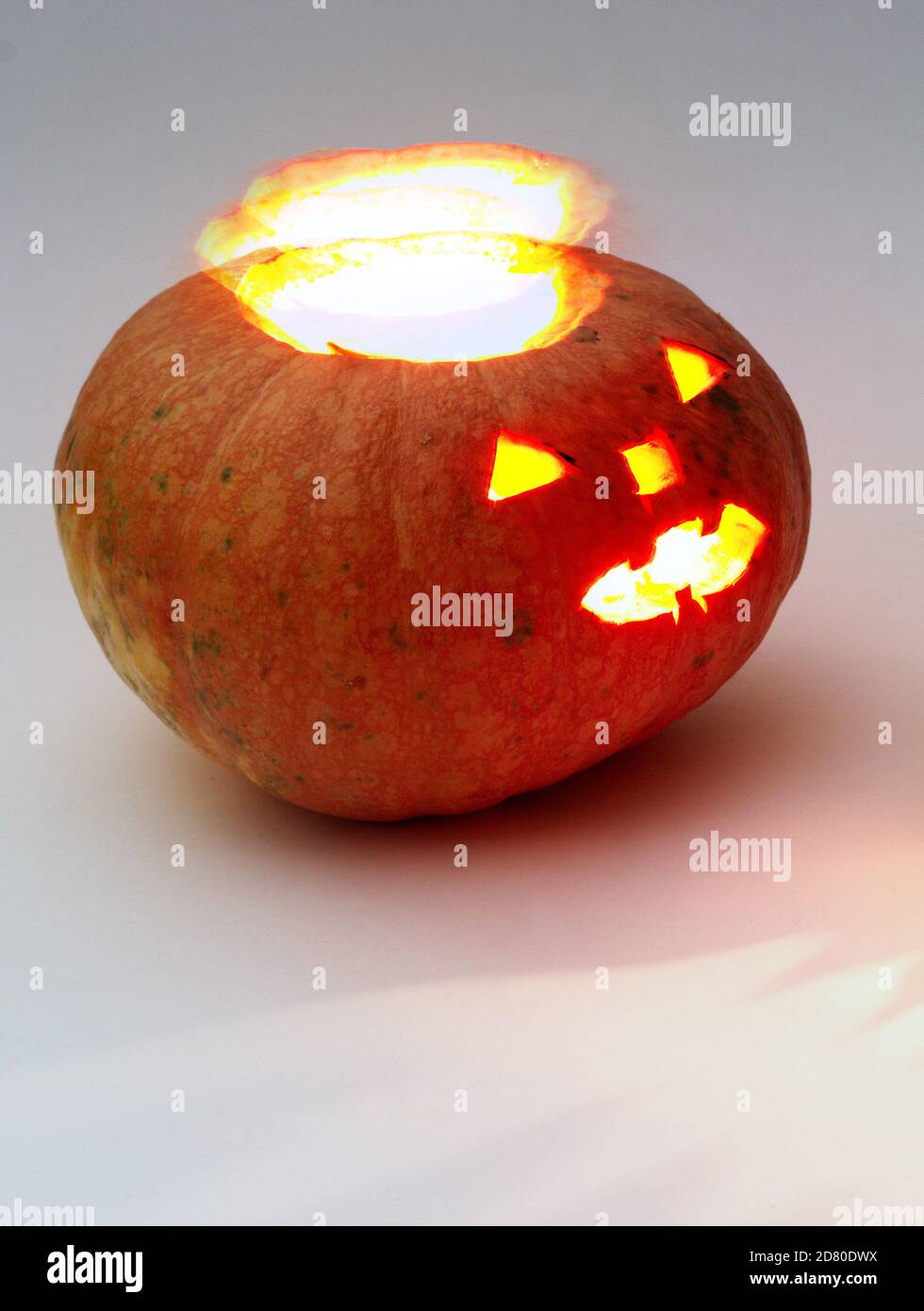 zucca di halloween. bagliore simile a un alone si separa dalle entrail. Zucca rotonda arancione con facce grossolanamente scolpite con lanterna lucente all'interno Foto Stock