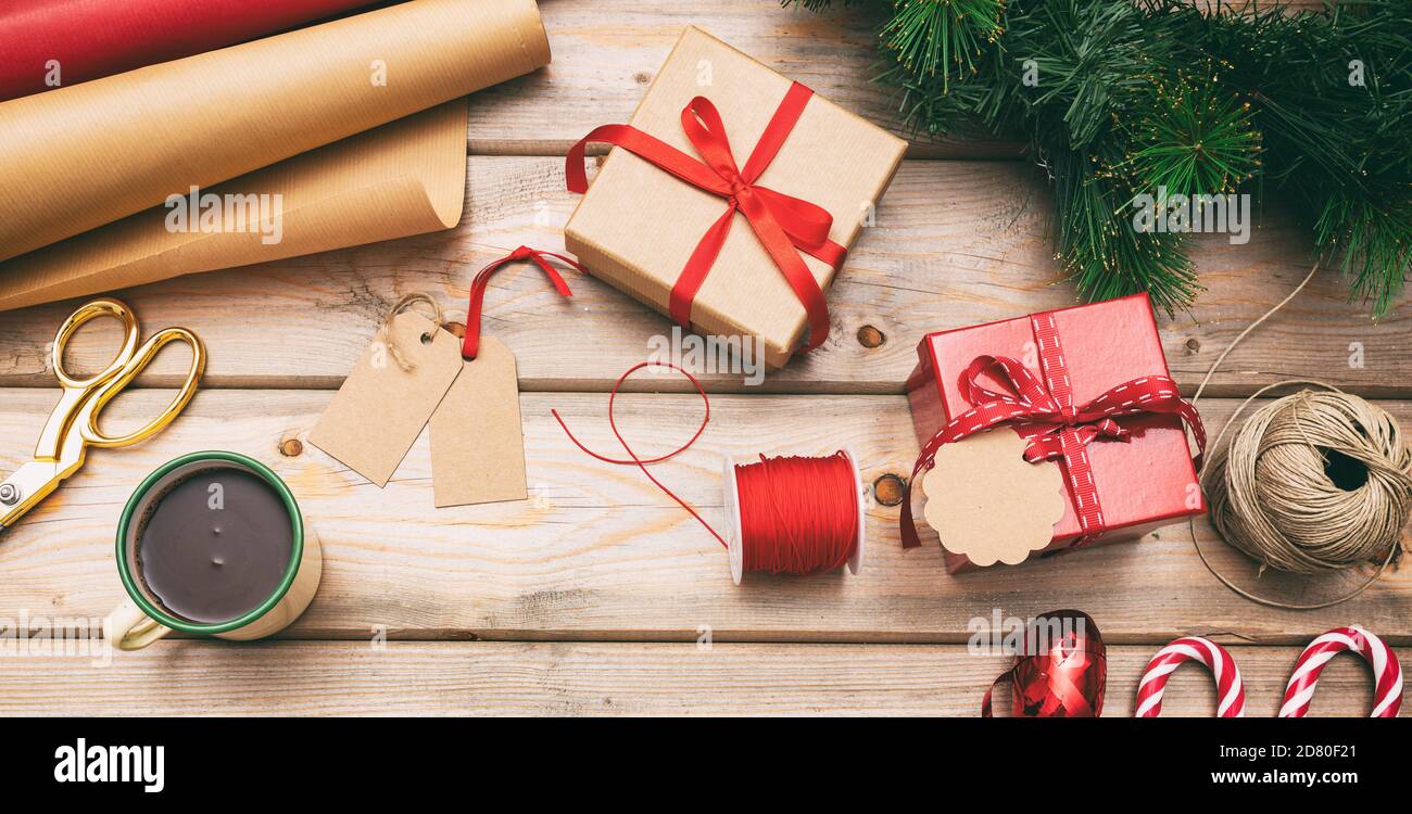 Preparazione di Natale. Le scatole regalo che avvolgono il piatto sono adagiato su sfondo di legno, vista dall'alto Foto Stock