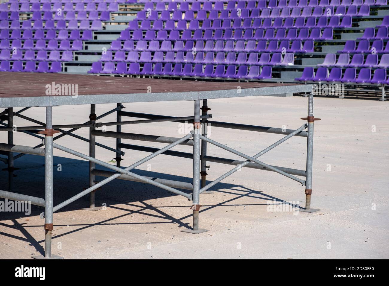 Posti a sedere in background. File di sedie vuote in plastica blu e tribuna arrugginita. Teatro, mostre, spettacoli, festival o concerti per il pubblico a su Foto Stock