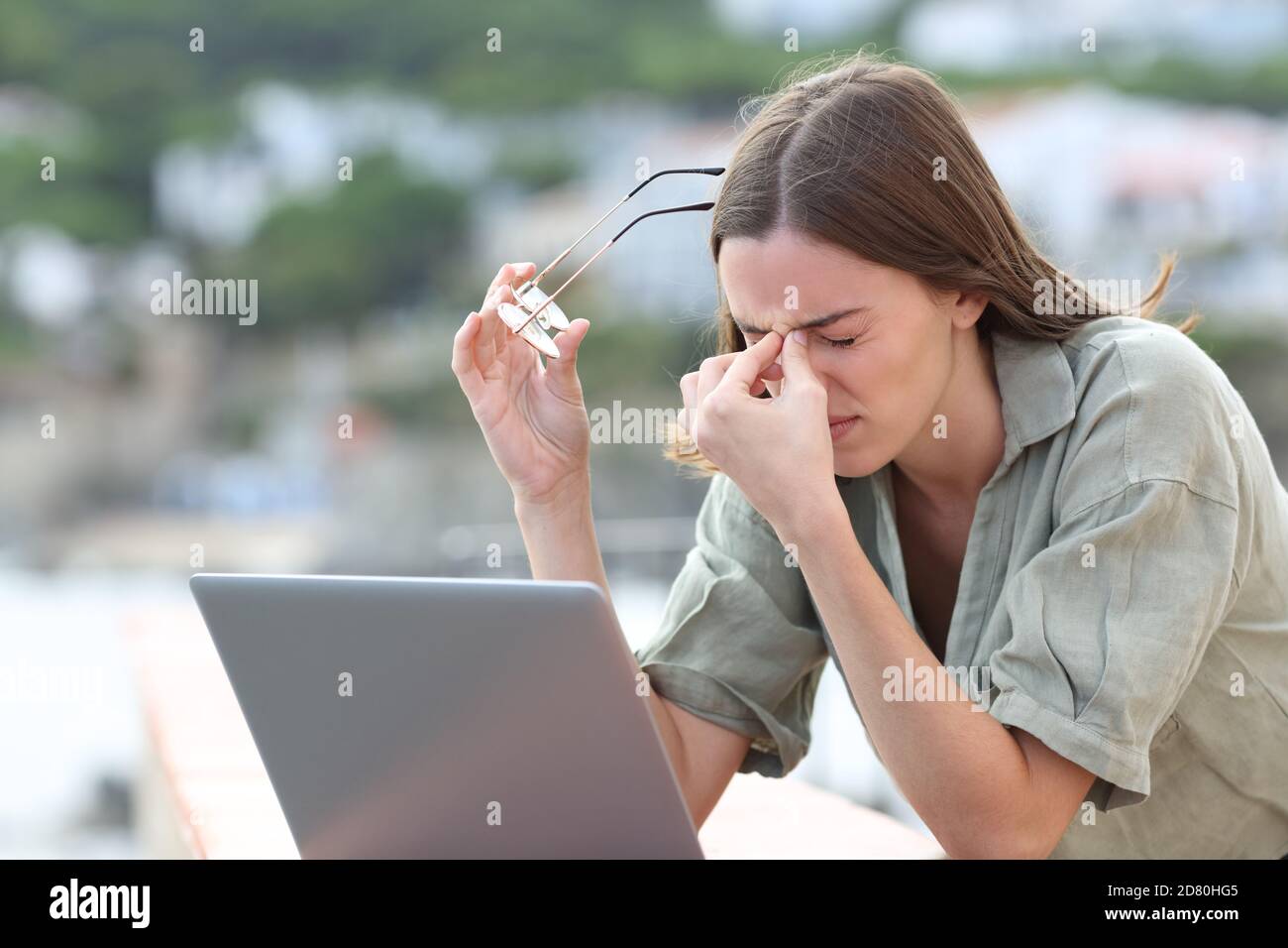 Donna stressata che usa il laptop che soffre di eyestrain lamentandosi all'aperto in un balcone Foto Stock