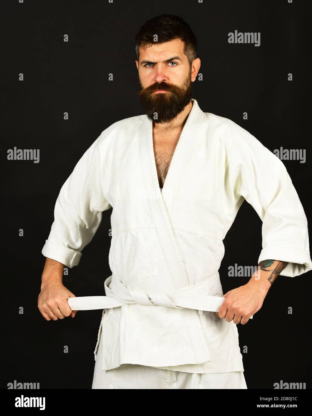 Uomo con barba in kimono bianco su sfondo nero. Stile di vita sano e  concetto sportivo. Karate uomo con volto stretto in uniforme. Cintura bianca  di Jiu Jitsu master Ties Foto stock -