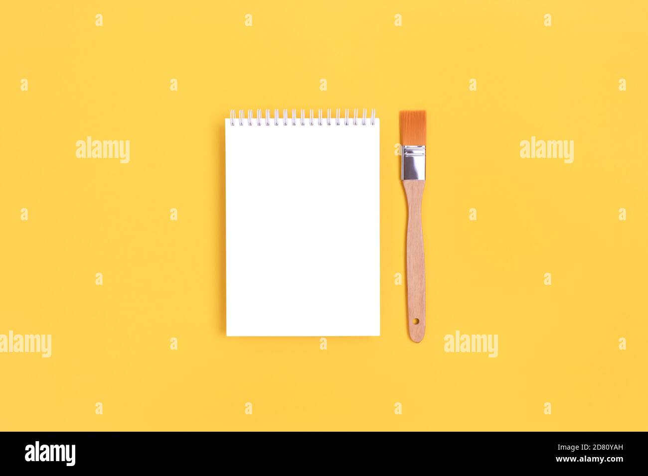Modello di notebook vuoto con pennello su sfondo giallo brillante. Mokup artistico. Foto Stock