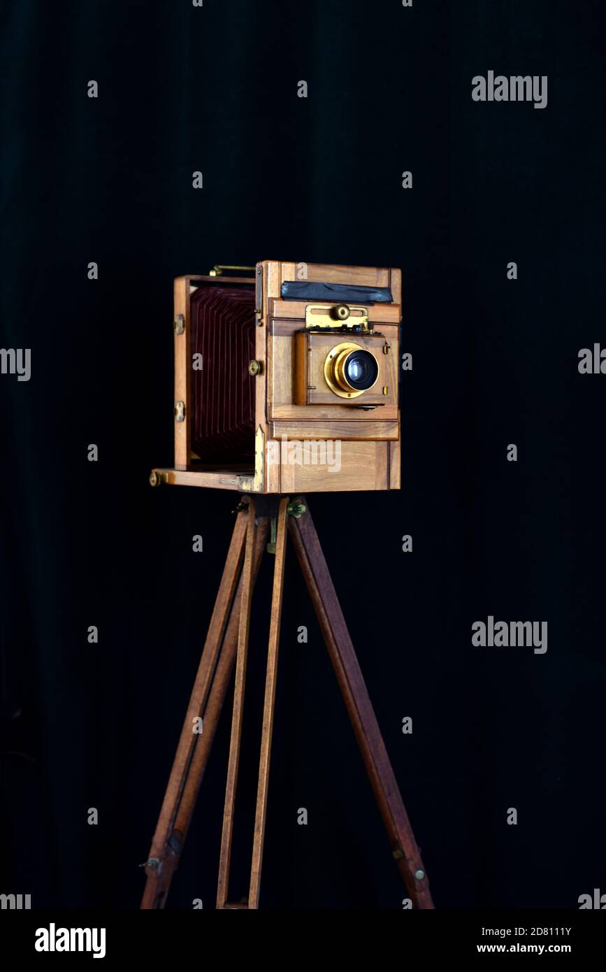 Antica fotocamera da studio a piastra completa in legno di mogano con ottone Accessori Spara su sfondo nero con treppiede in legno d'epoca Foto Stock