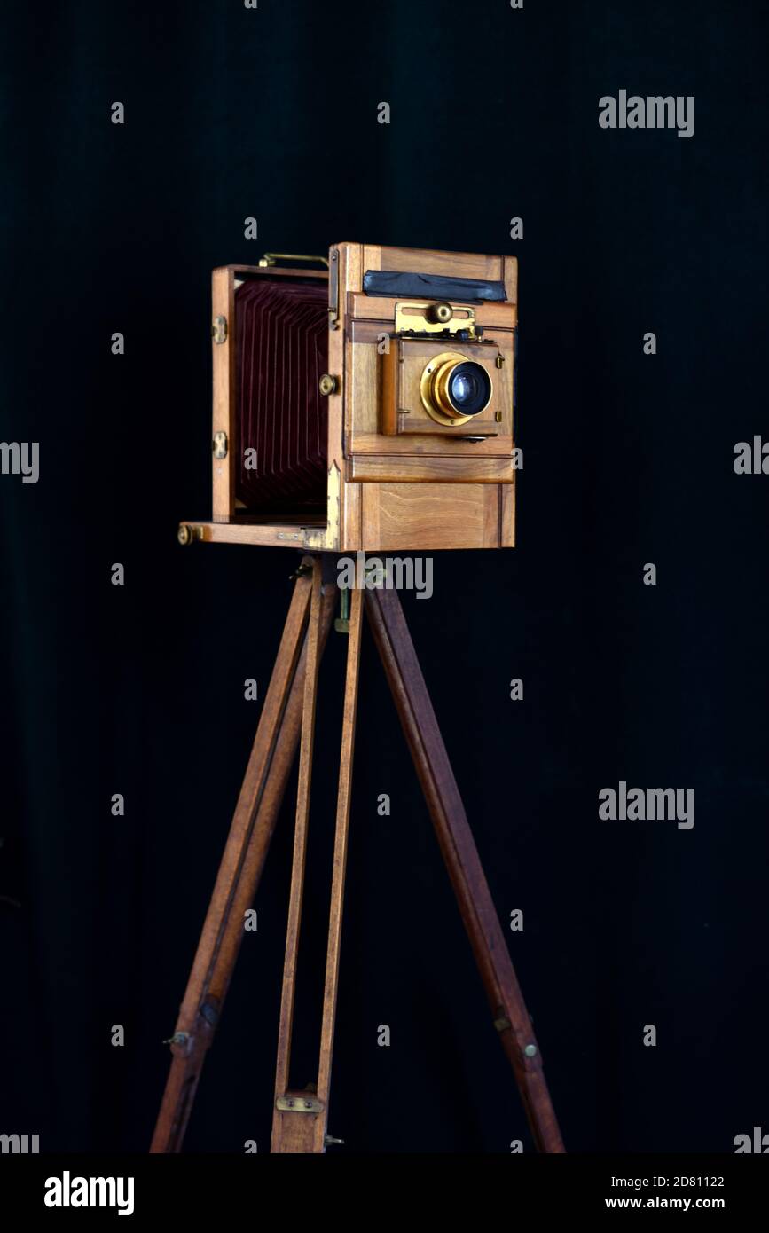 Antica fotocamera da studio a piastra completa in legno di mogano con ottone Accessori Spara su sfondo nero con treppiede in legno d'epoca Foto Stock