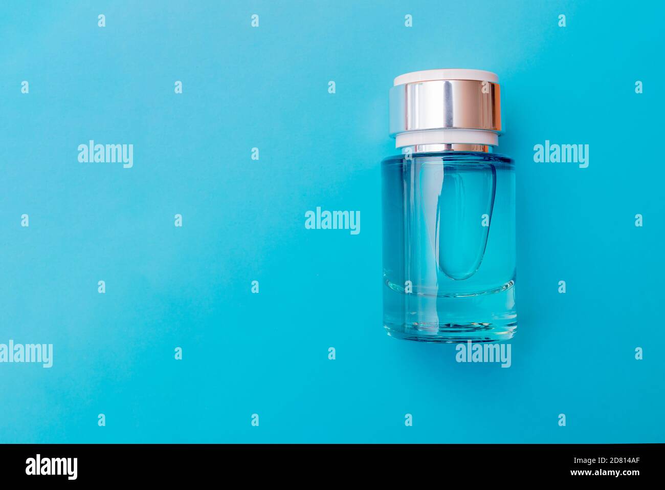 Composizione bottiglia di profumo in vetro, posa piatta vista dall'alto foto sfondo azzurro. Foto Stock