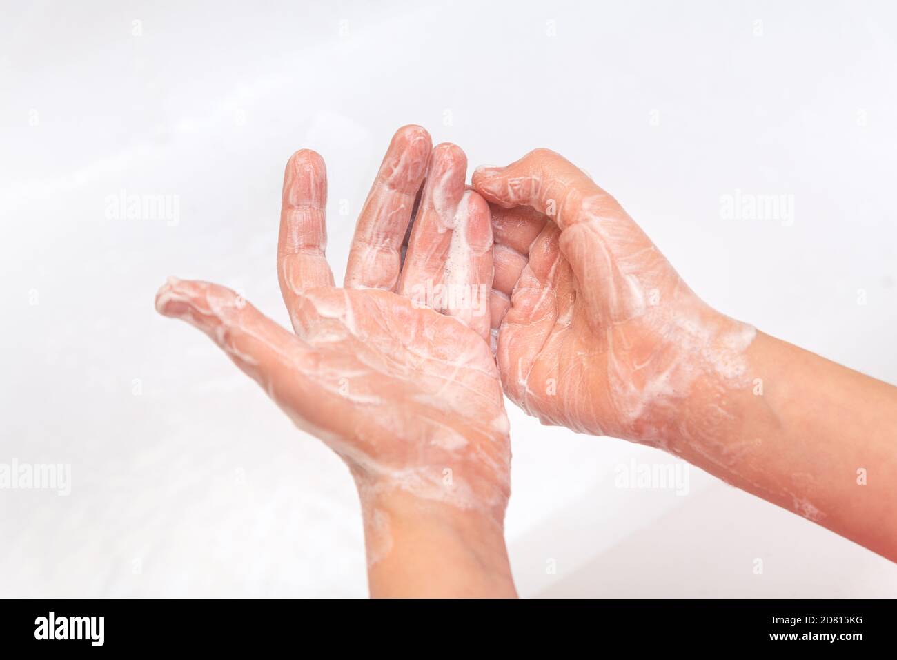 Bambino lisce le mani con un sapone da vicino su uno sfondo bianco. Concetto di igiene. Prevenzione delle malattie, assistenza sanitaria, cura del corpo. Protezione da virus. Pande Foto Stock