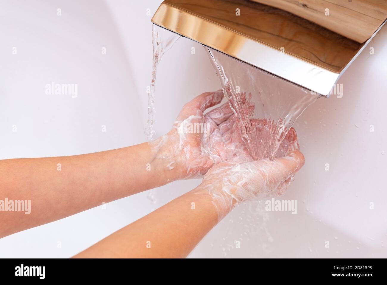 Il bambino le lava le mani con sapone sotto l'acqua corrente. Capretto saponato`s mani da vicino su uno sfondo bianco. Concetto di igiene. Preventi di malattia Foto Stock