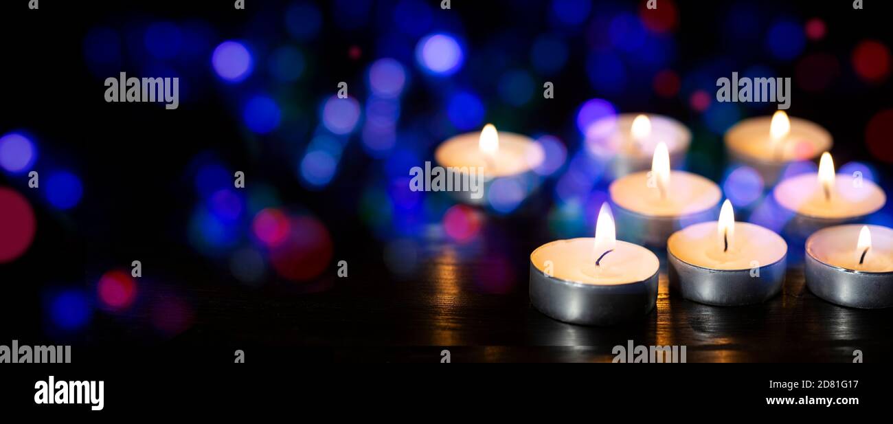 Candele che bruciano in un buio con bokeh colorato Foto Stock