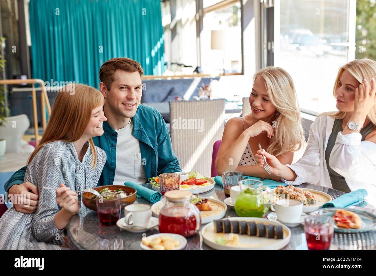 felici giovani amici caucasici che si riuniscono in caffetteria, seduti a tavola, chiacchierando, parlando.they stanno trascorrendo il tempo divertente, gli studenti o i migliori amici che si incontrano Foto Stock
