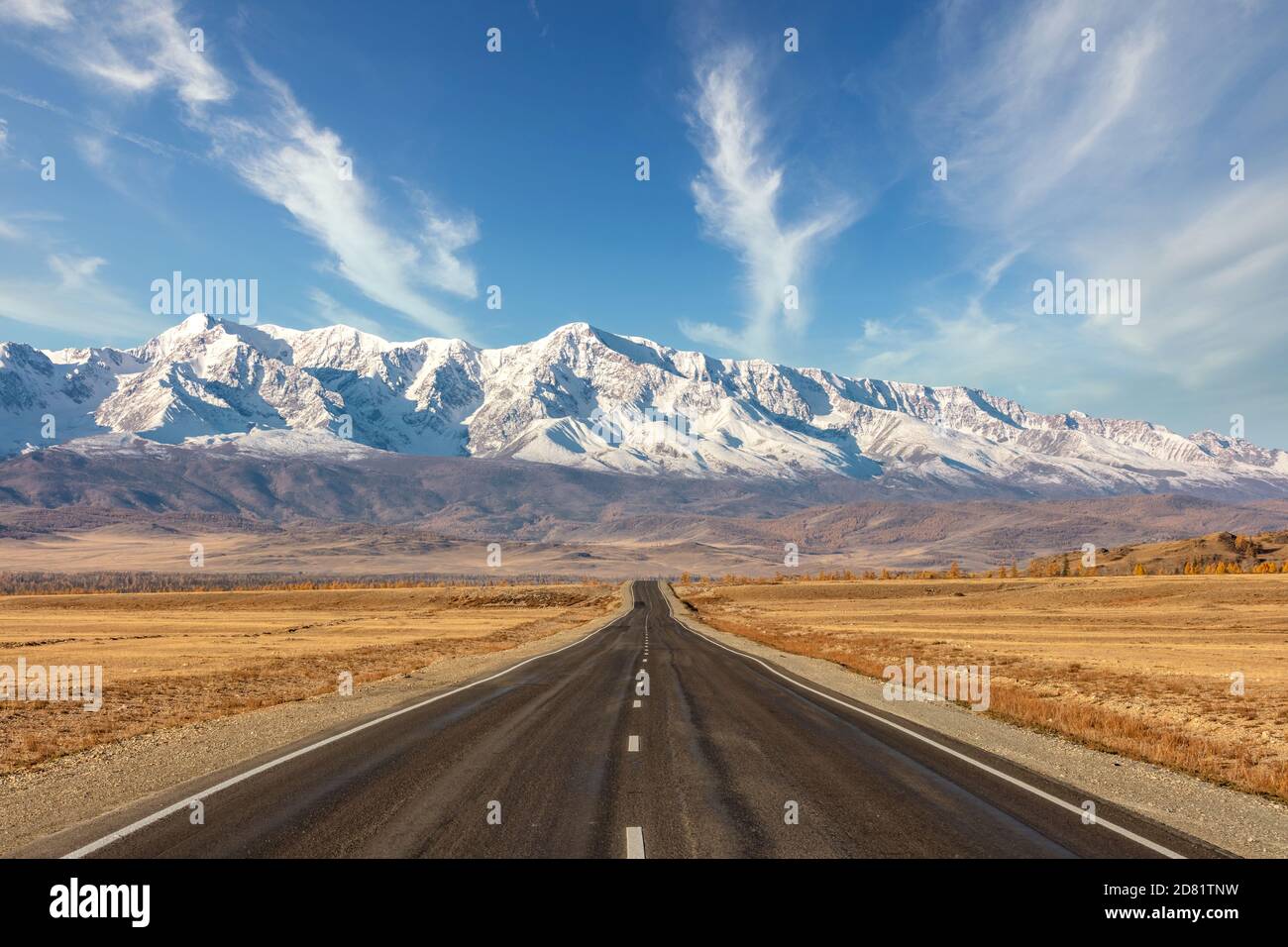 Ripresa di un'autostrada vuota e diritta che conduce alle vette innevate della catena montuosa del Kuray. Bel cielo blu nuvoloso come sfondo. Altai Mountains, S. Foto Stock
