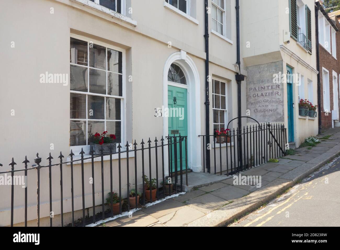 Casa georgiana e porta, con vecchio segno per un pittore e glazier dipinto su un vecchio muro di negozio, Hastings Old Town, East Sussex, Regno Unito Foto Stock