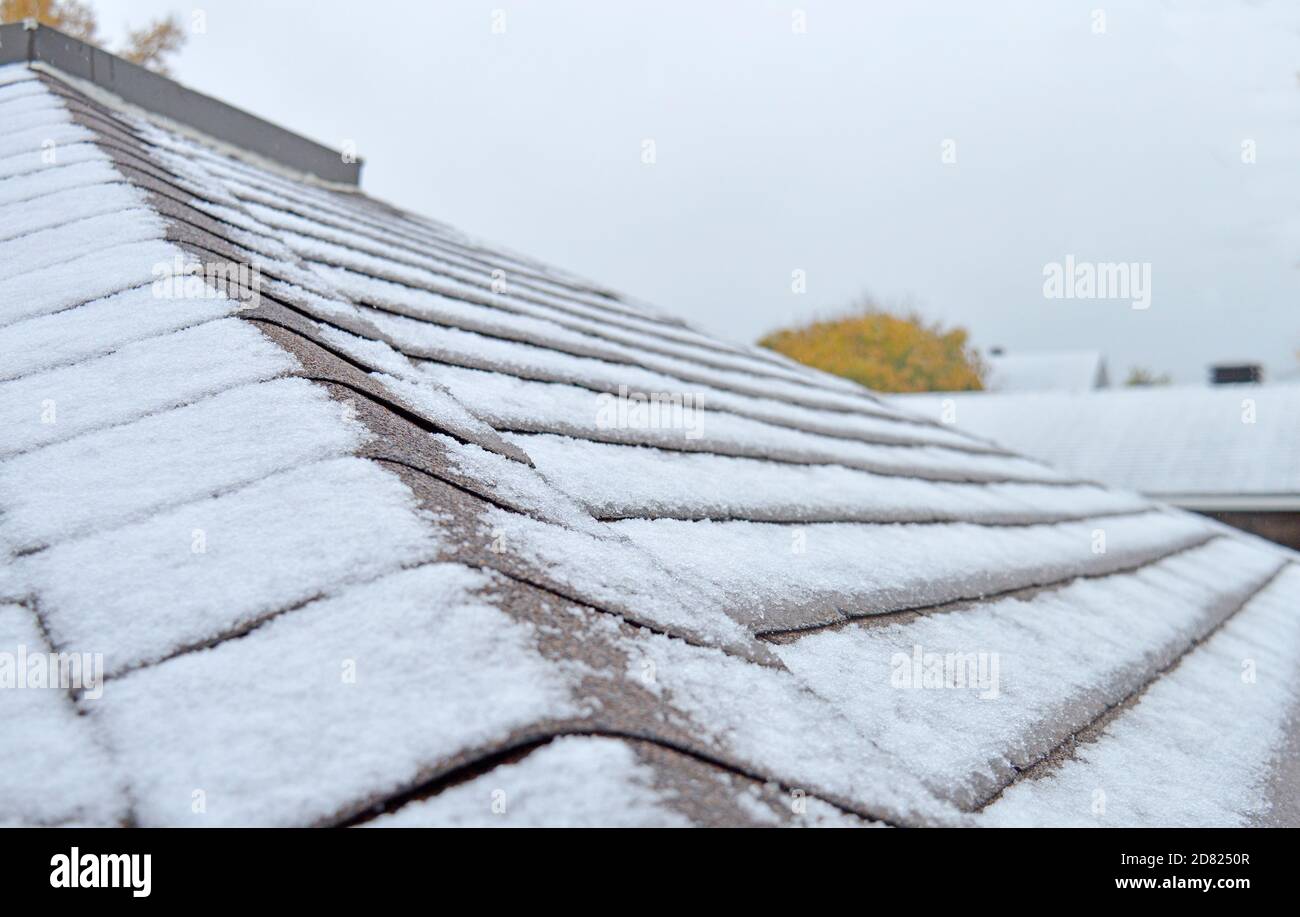 Neve appena caduta su un tetto con case aggiuntive sullo sfondo, intenzionalmente sfocata Foto Stock