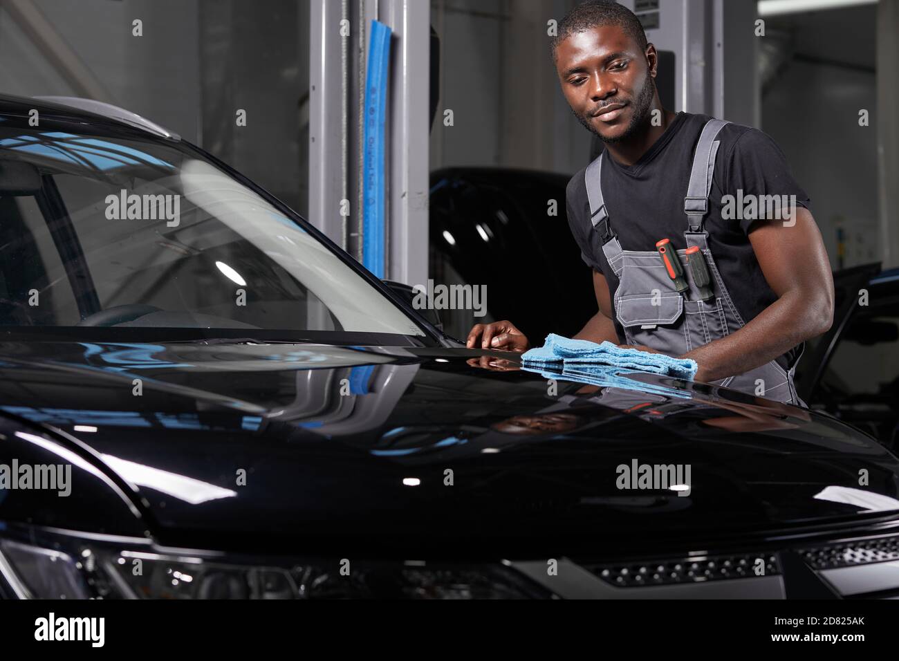 giovane adulto afro americano uomo auto di pulizia con panno microfibra, dettagli auto o concetto di valeting Foto Stock