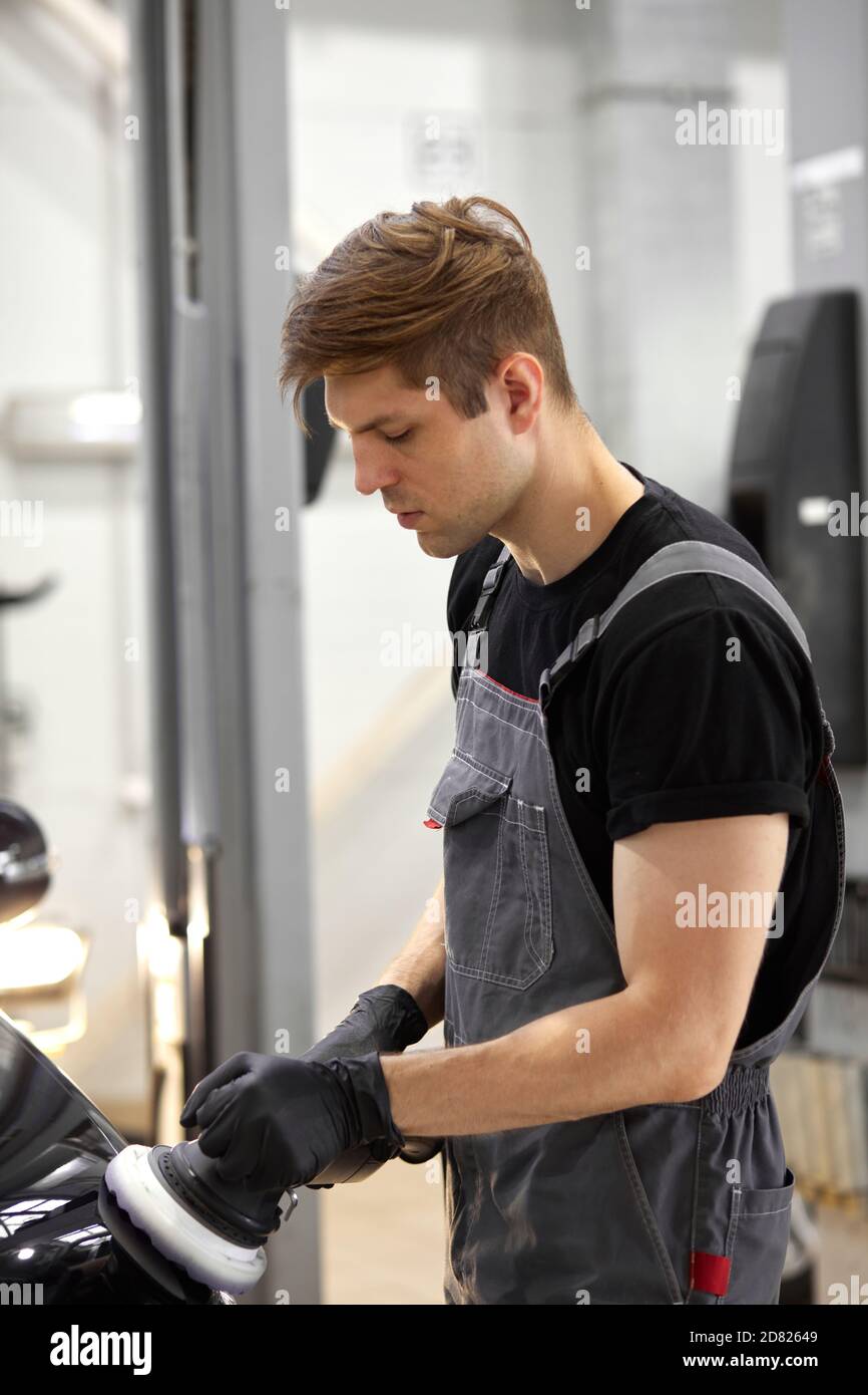 dettagli auto e lucidare concetto. giovane caucasico professionale di servizio auto lavoratore maschile, auto meccanica con lucidatrice orbitale, concetto di automobile Foto Stock