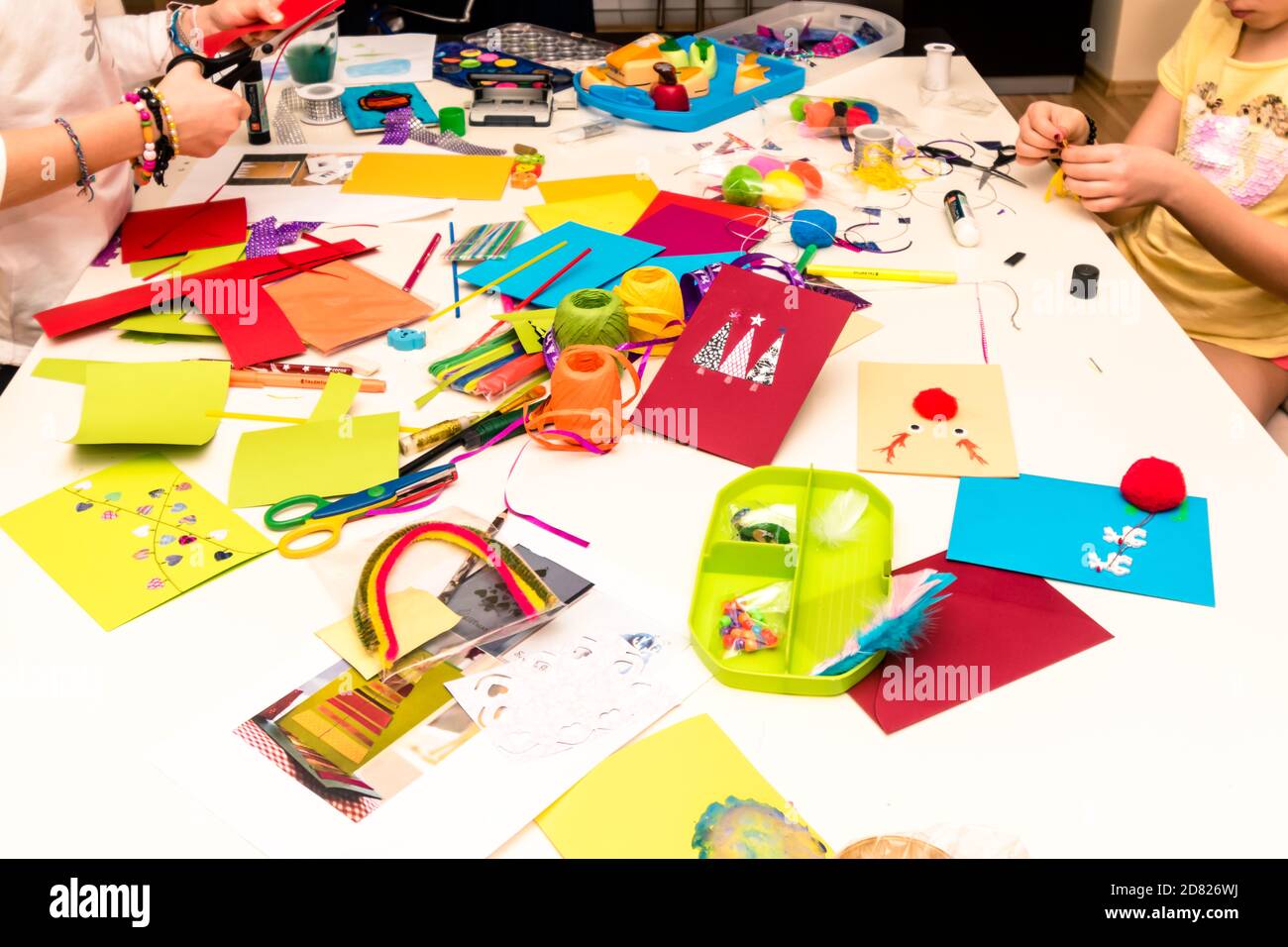carte colorate, forbici, colla, cannucce, matite, nastri, pizzi sul tavolo preparati per la creazione di biglietti d'auguri natalizi Foto Stock