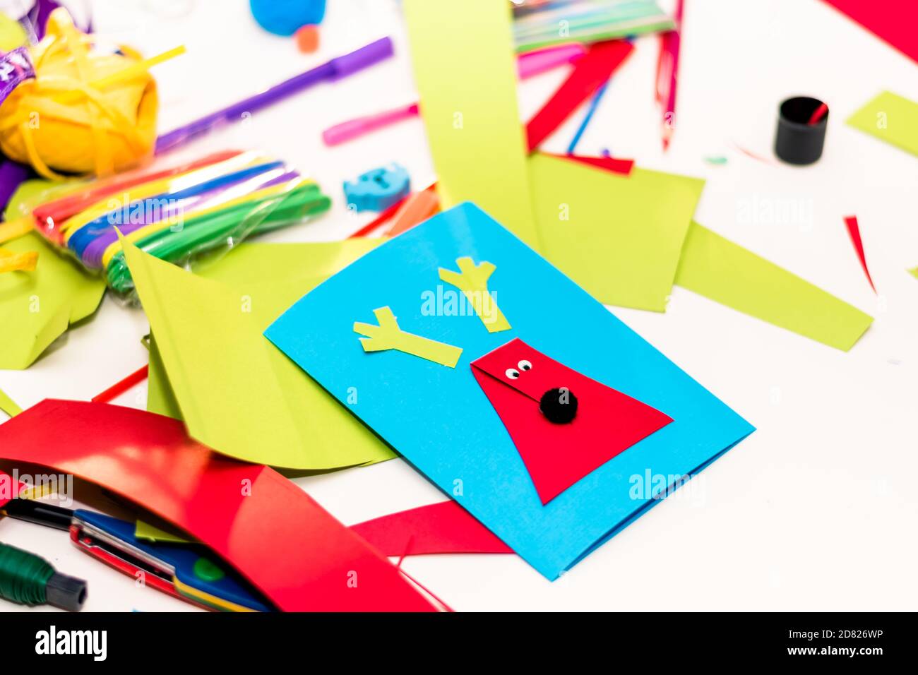 carte colorate, forbici, colla, cannucce, matite, nastri, pizzi sul tavolo preparati per la creazione di biglietti d'auguri natalizi Foto Stock