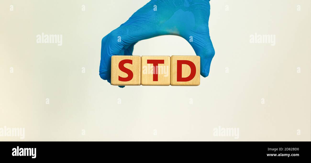 Concetto medico STD. La mano in guanto blu contiene i cubetti di legno con l'iscrizione 'TD - malattia sessualmente trasmessa'. Splendido sfondo bianco. Copia Foto Stock