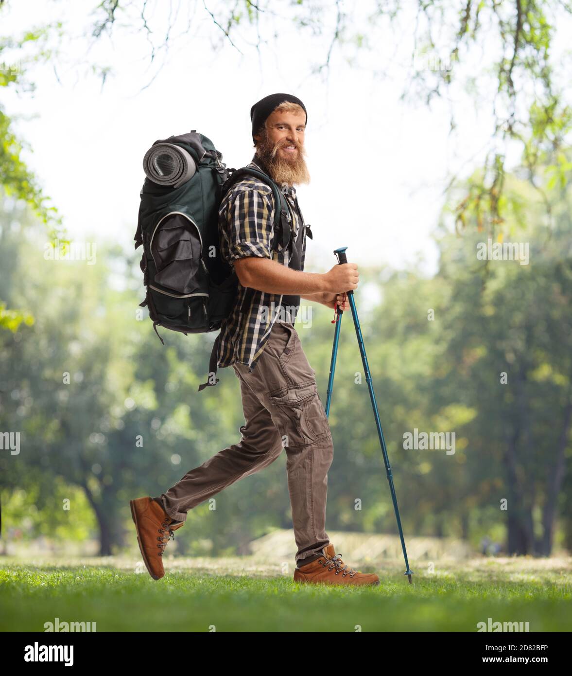 Foto di profilo a lunghezza intera di un escursionista con un zaino e bastoni escursionistici a piedi nella natura Foto Stock