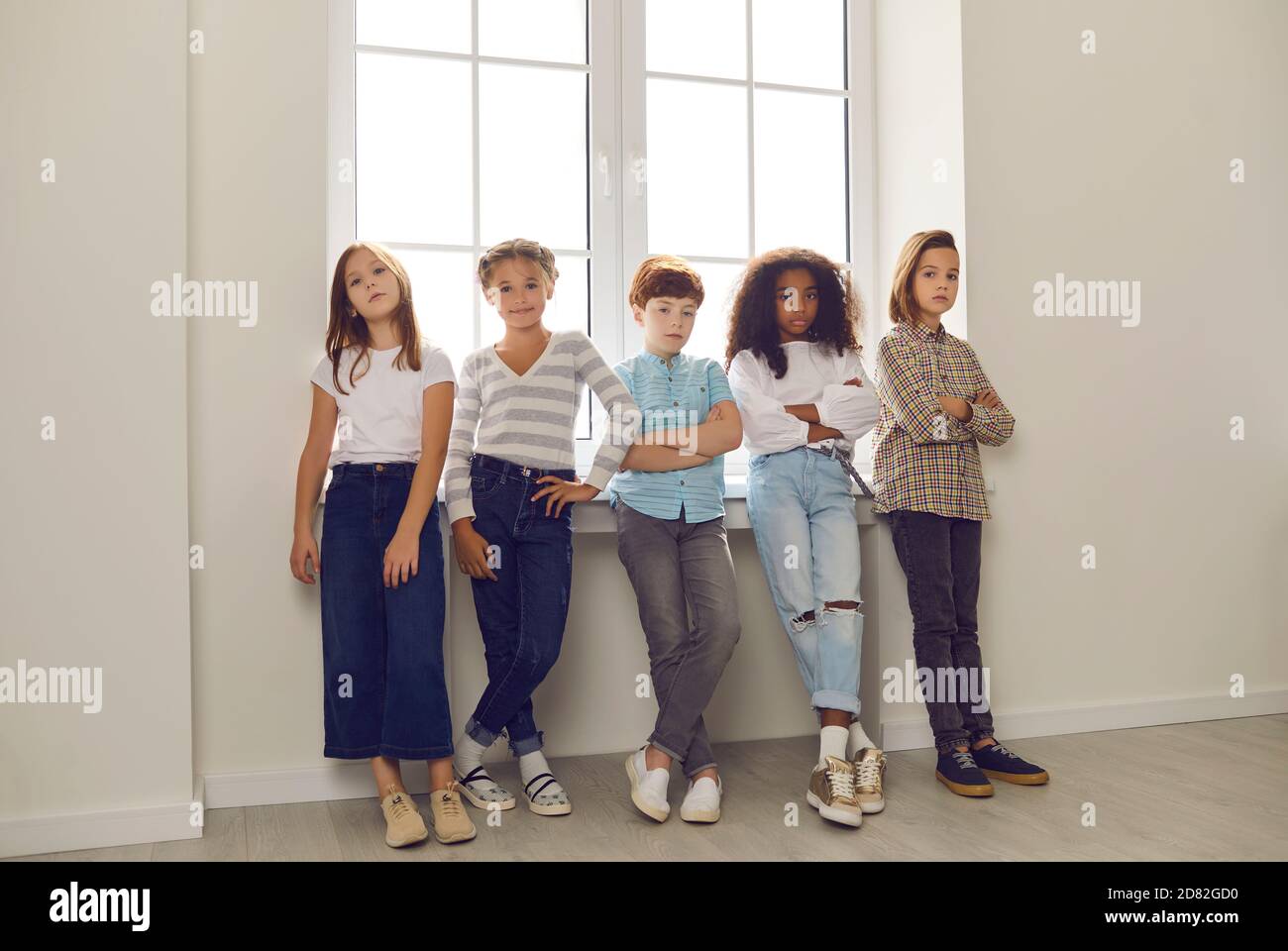 Gruppo di amici diversi in piedi vicino alla finestra e guardando la fotocamera nel corridoio. Foto Stock