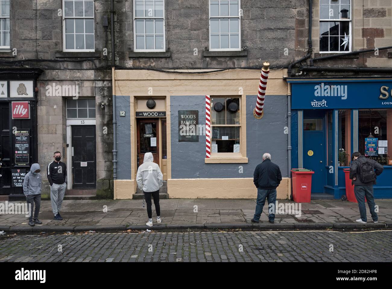Coda socialmente distanziata per Woods Barbers su Drummond Street, Edimburgo, Scozia, Regno Unito. Foto Stock