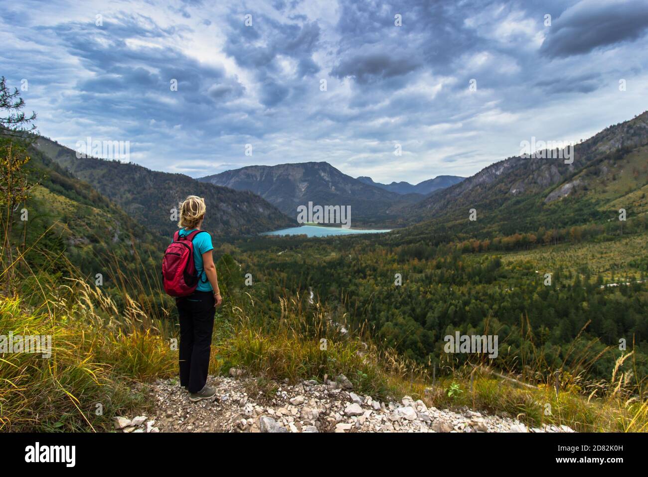 Ragazza sportiva attiva che riposa sulla vetta delle Alpi, in Austria. Backpacker godendo della vista delle montagne e del lago. Wanderlust concetto di libertà di viaggio Foto Stock