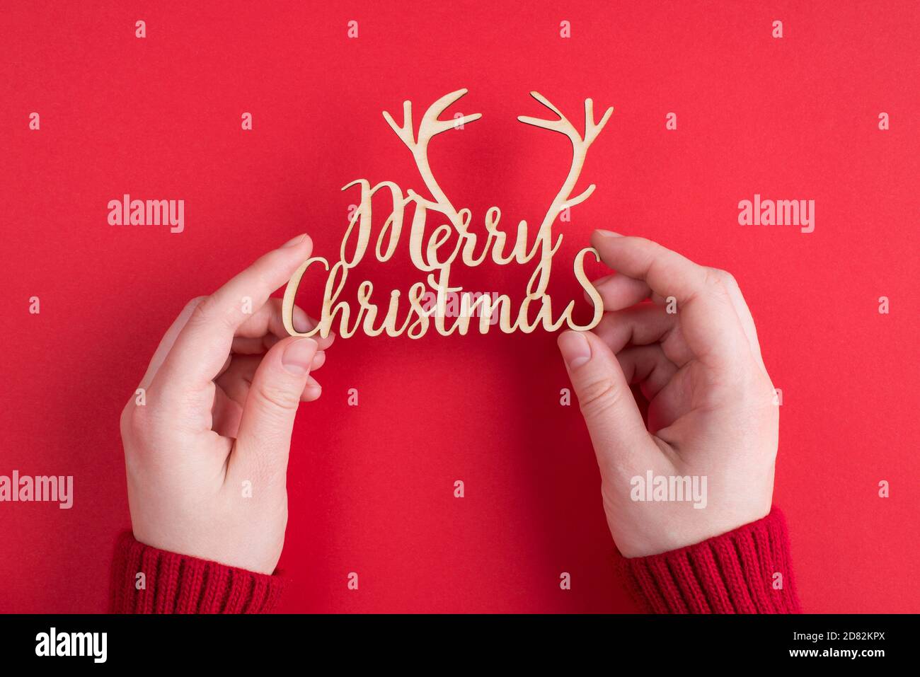 Buon Natale test concetto. Sopra pov in prima persona vedere la foto delle mani che tengono il saluto vacanza testo isolato su rosso brillante colore backgro Foto Stock