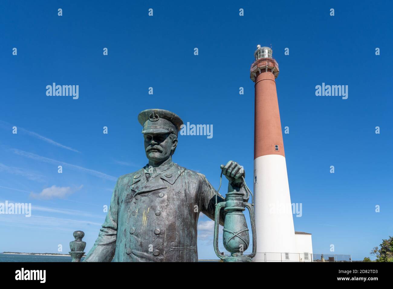 Barnegat Light, NJ - 15 ottobre 2020: Statua in bronzo intitolata 'Lighthouse Keeper' di Brian Hanlon al Barnegat Lighthouse state Park con il faro Foto Stock