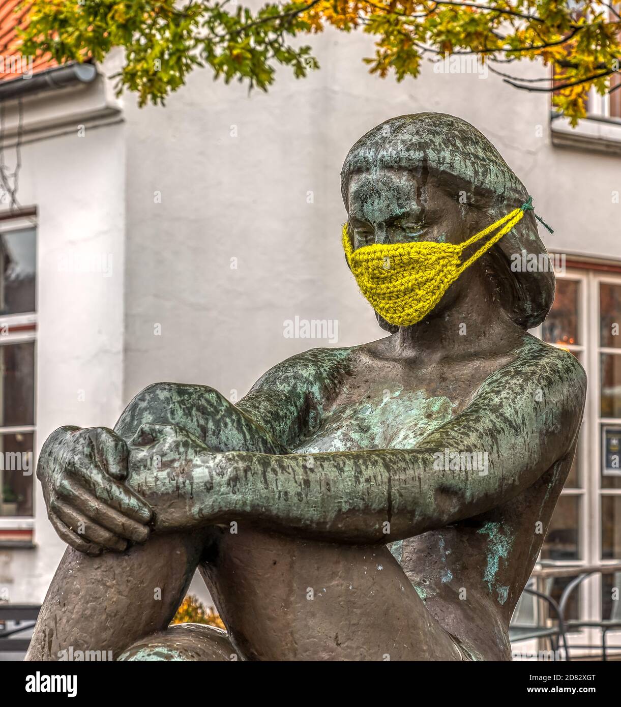 Statua in bronzo di una ragazza seduta che indossa una maschera gialla a maglia contro covid-19, Frederikssund, Danimarca, 26 ottobre 2020 Foto Stock