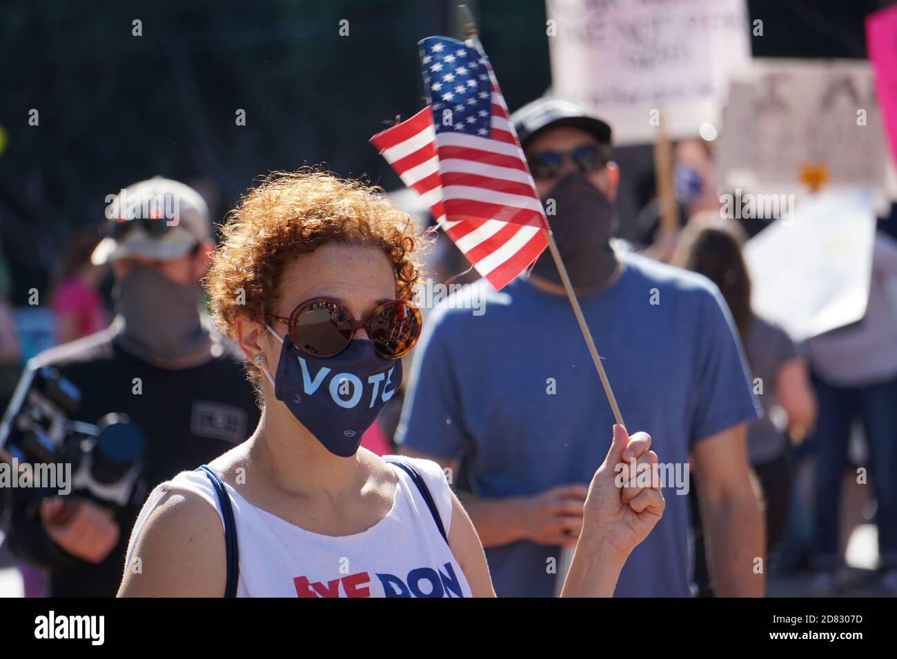 17 ottobre 2020. San Francisco - la marcia delle donne. Il protester indossa una maschera di voto e detiene una bandiera americana poco prima delle elezioni USA del 2020. California. Foto Stock