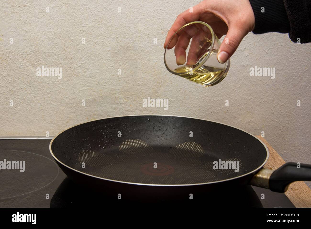 Mettere il bio-olio nella teglia nera calda dal bicchiere Foto Stock