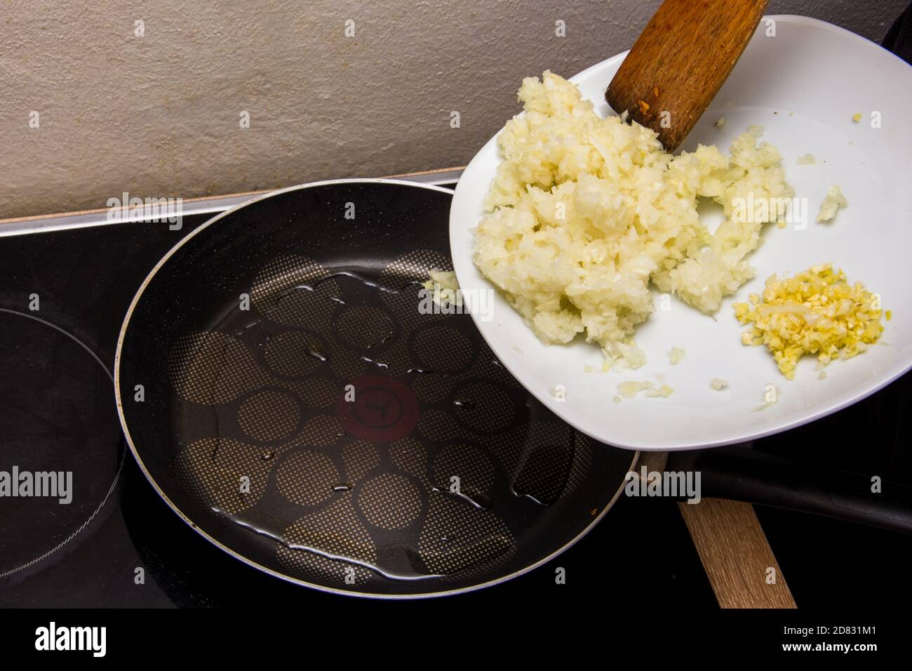 Mettere la cipolla e l'aglio tagliati in oro nella padella calda con olio Foto Stock