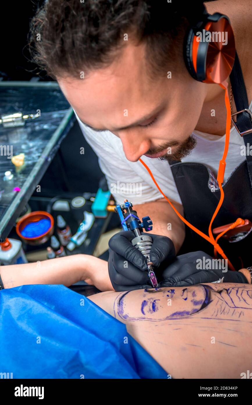 Tattooer lavora su una pistola professionale per tatuaggio in tatuaggio salone Foto Stock