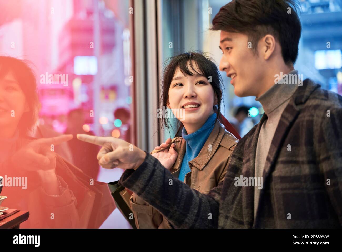 giovane coppia asiatica amorevole che guarda la vetrina e parla Foto Stock