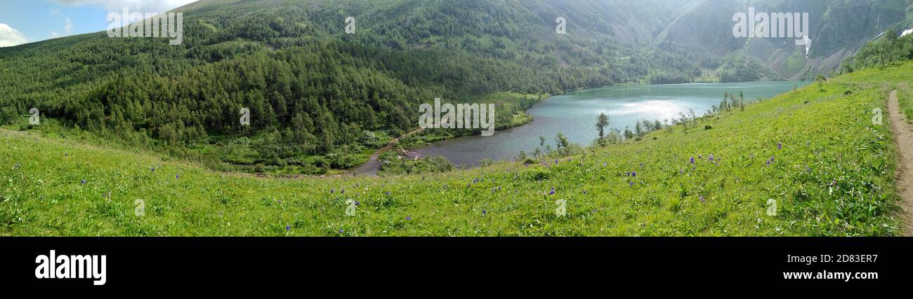 Ripresa panoramica di un lago alpino adagiato in una conca dai bordi nevosi. Laghi di Ivanovskie, Khakassia, Sud Siberia, Russia. Foto Stock