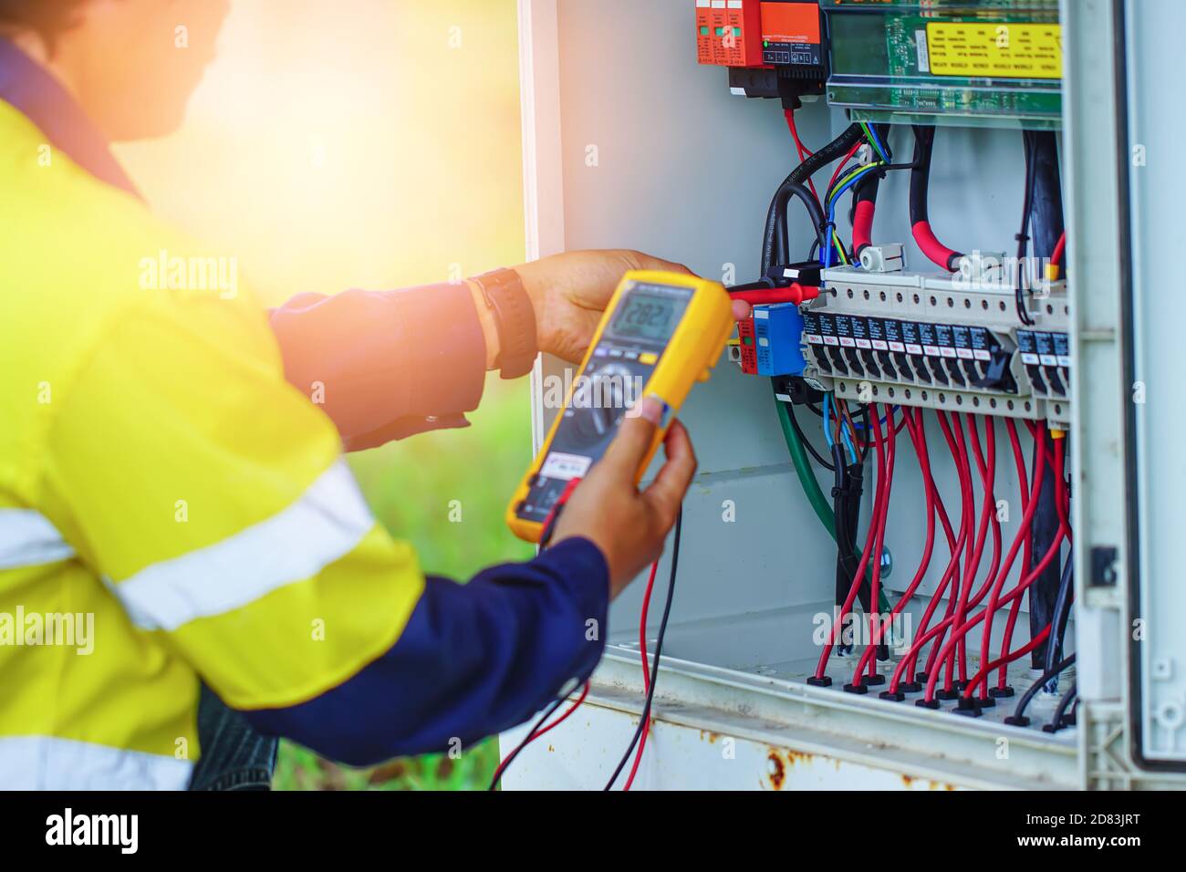 Gli operatori utilizzano il multimetro per misurare la tensione dei fili elettrici prodotti dall'energia solare per confermare il normale funzionamento dei sistemi. Foto Stock