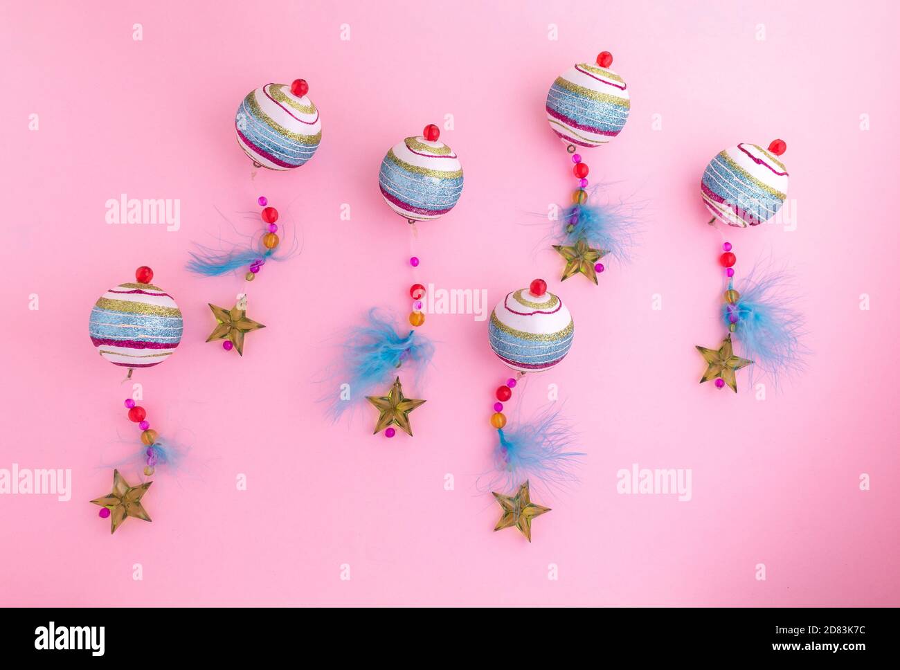 Colorate palline natalizie decorate con piume, perle e stelle su sfondo rosa. Decorazione di Natale Foto Stock