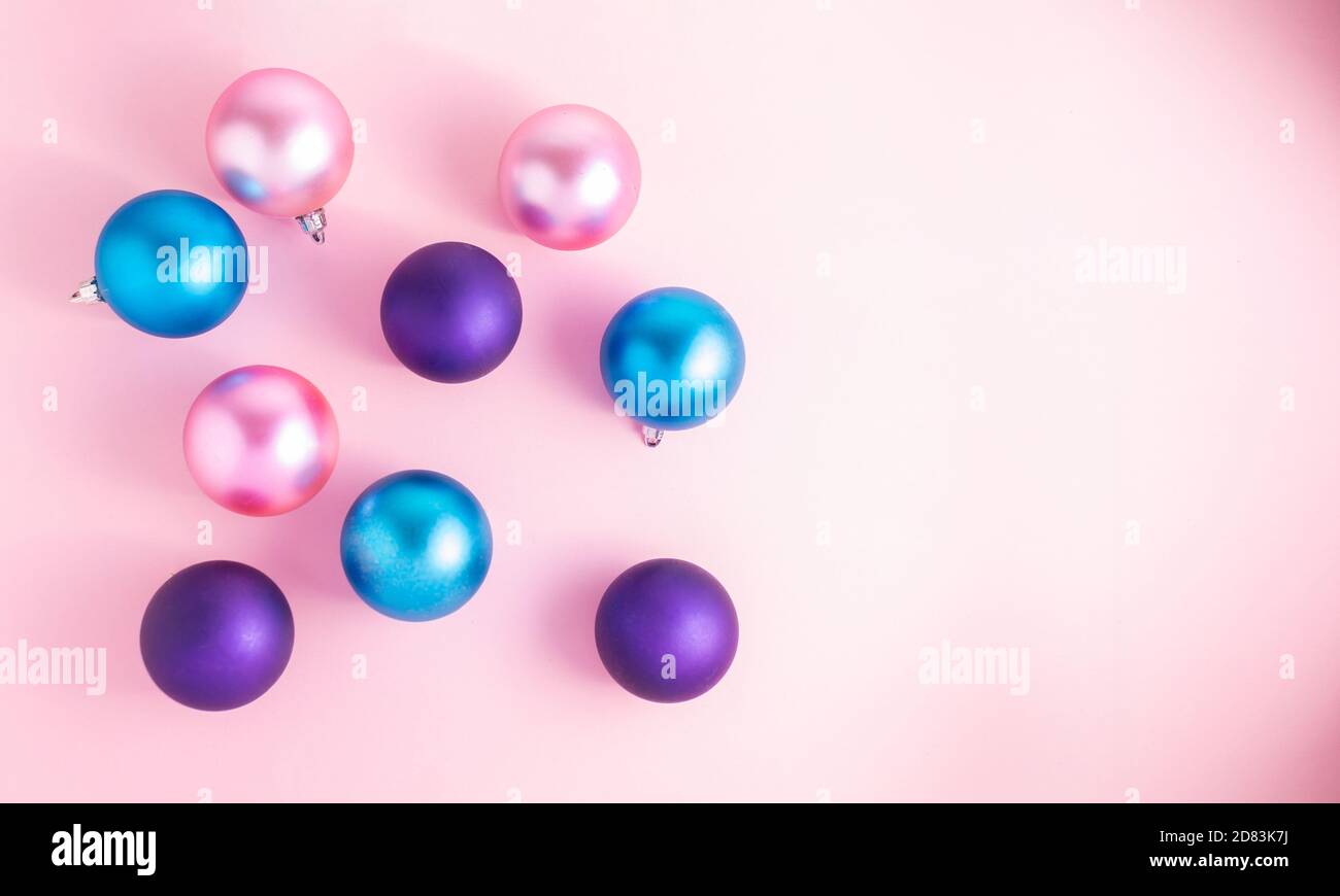 Palline di Natale in satin, rosa, viola e azzurro su sfondo rosa. Banner ideale per le festività di fine anno Foto Stock