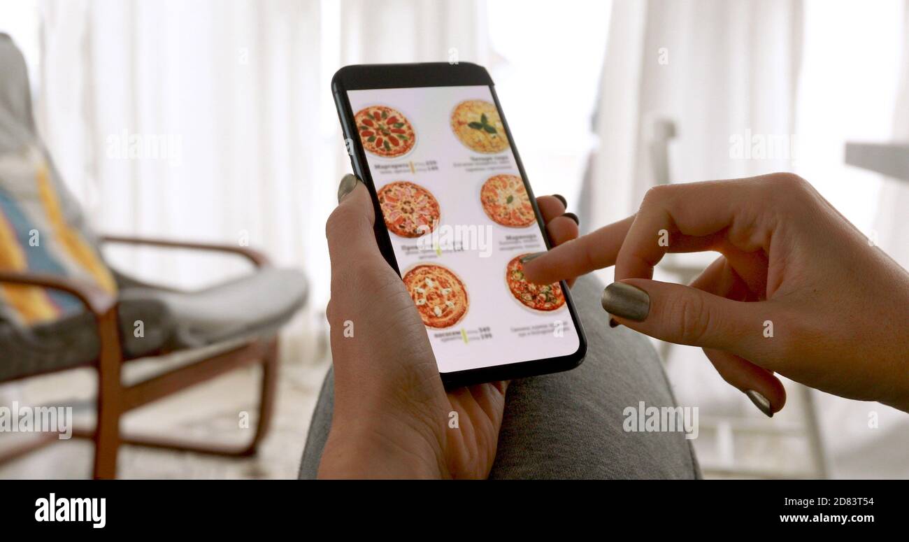 Donna che ordina la pizza a casa online Foto Stock