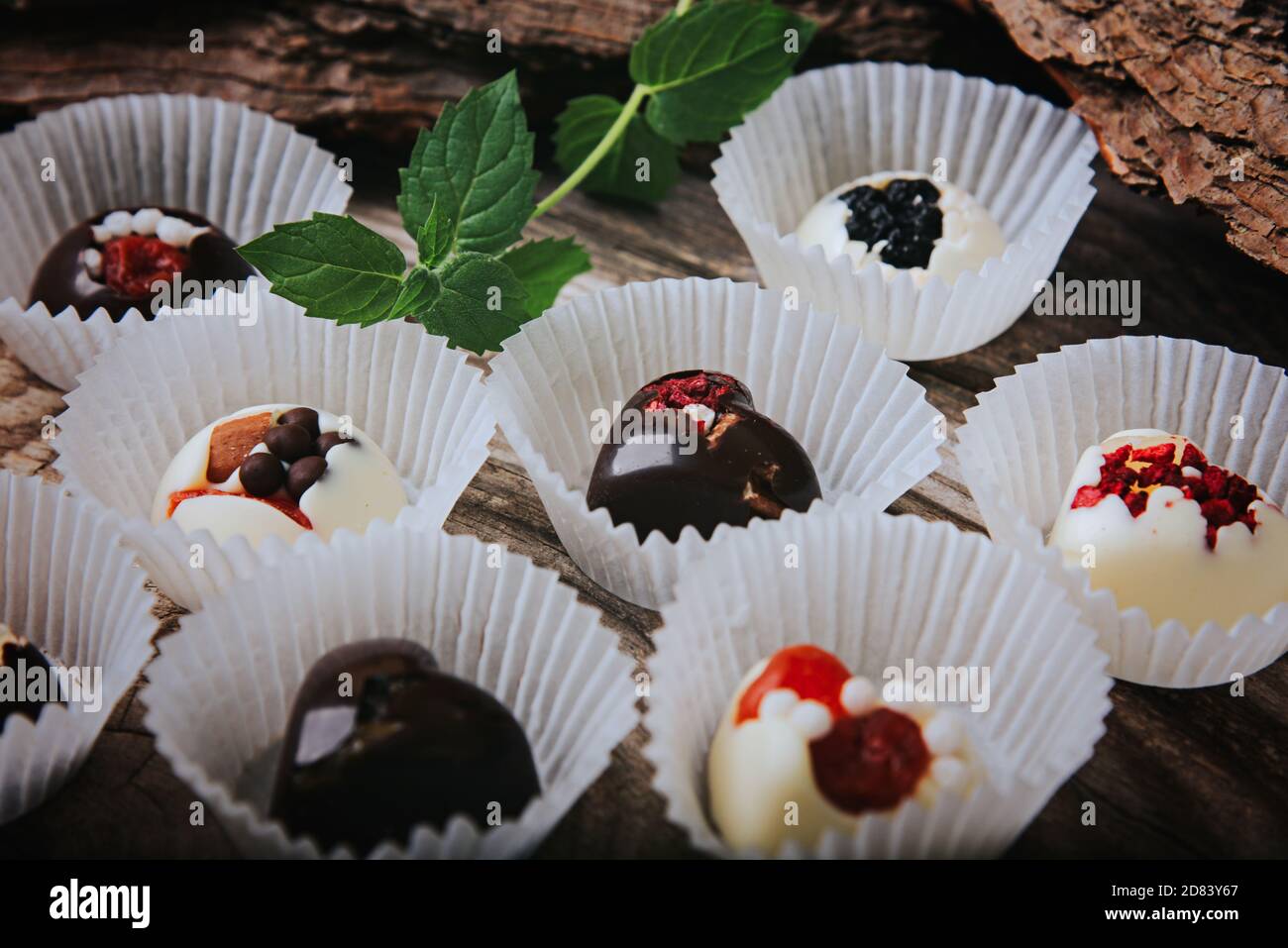 Tartufi artigianali di cioccolato su sfondo ligneo. Cioccolatini fatti a mano con frutta secca. Foto Stock