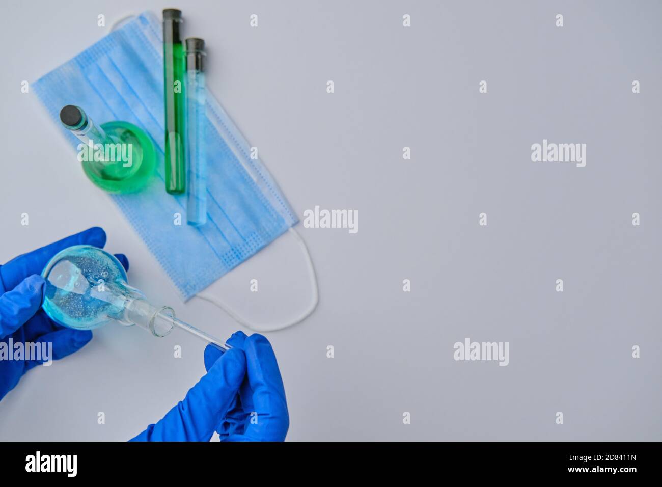 Scienziato che tiene la bacchetta di vetro e la fiasca al laboratorio, closeup. Chimica della soluzione. Soluzione antivirus Foto Stock