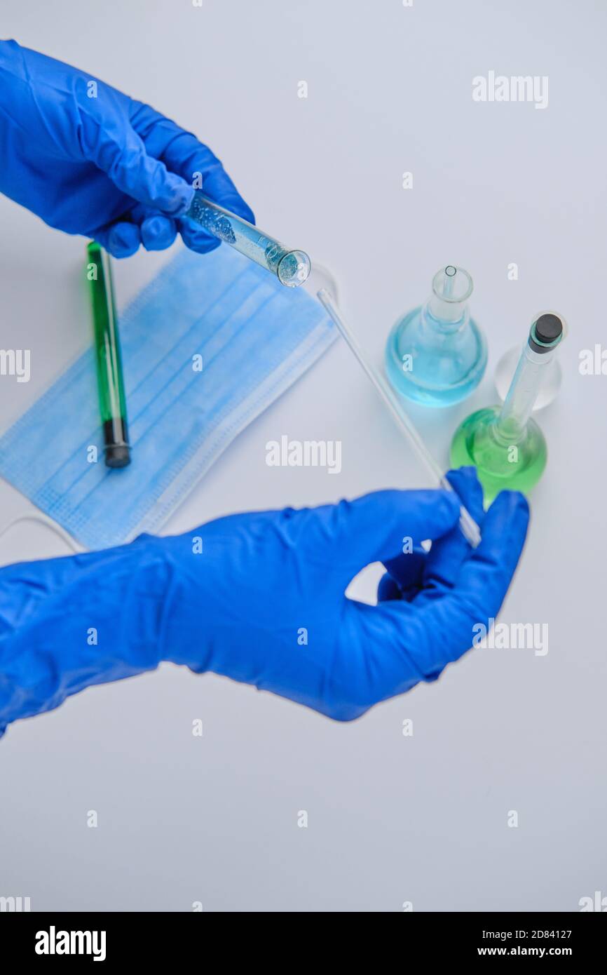 Scienziato che tiene l'asta e il tubo di vetro al laboratorio, primo piano. Chimica della soluzione. Soluzione antivirus Foto Stock