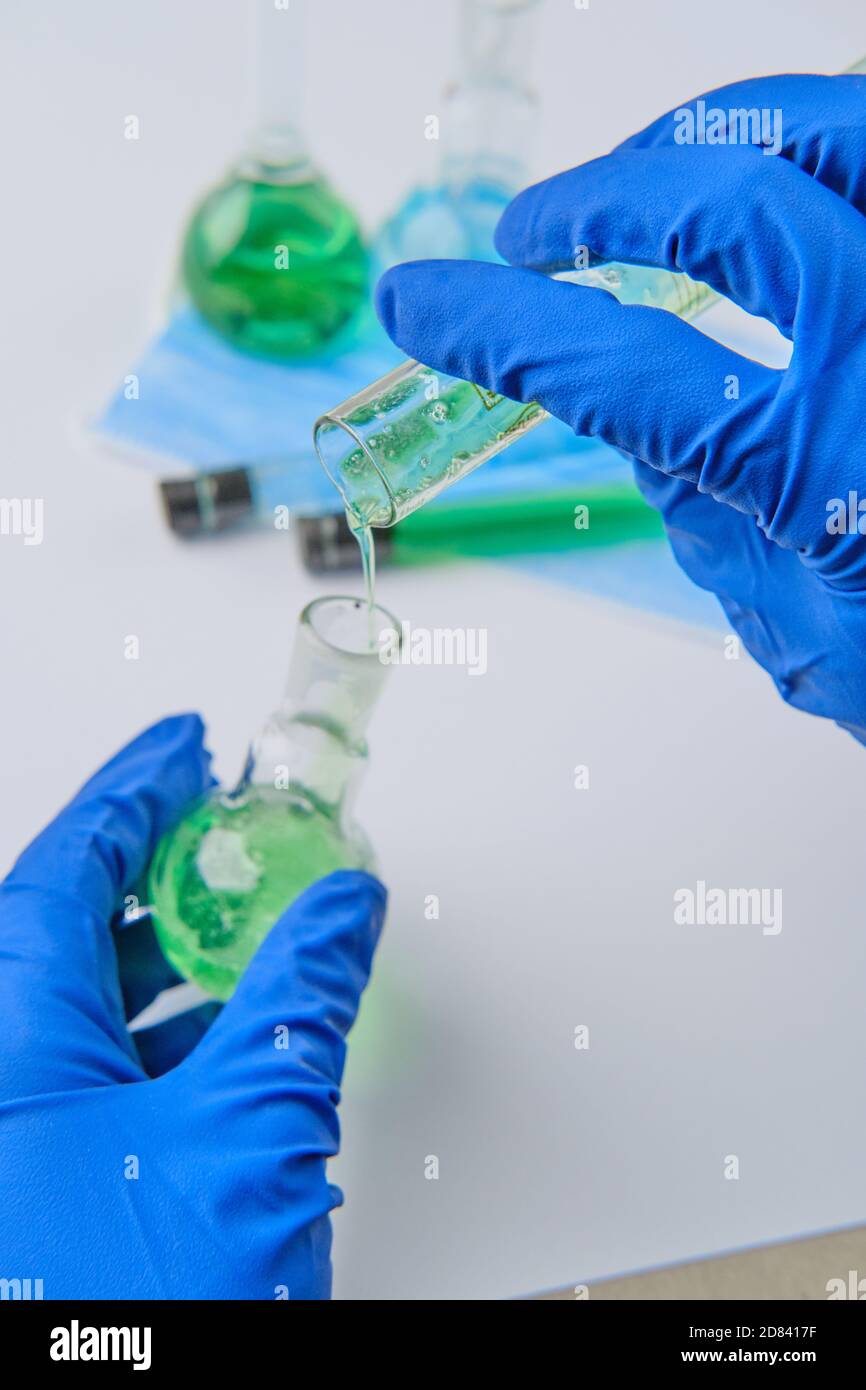 Matraccio e provetta da laboratorio per lo scienziato, closeup. Chimica della soluzione. Soluzione antivirus. Liquido blu e verde Foto Stock