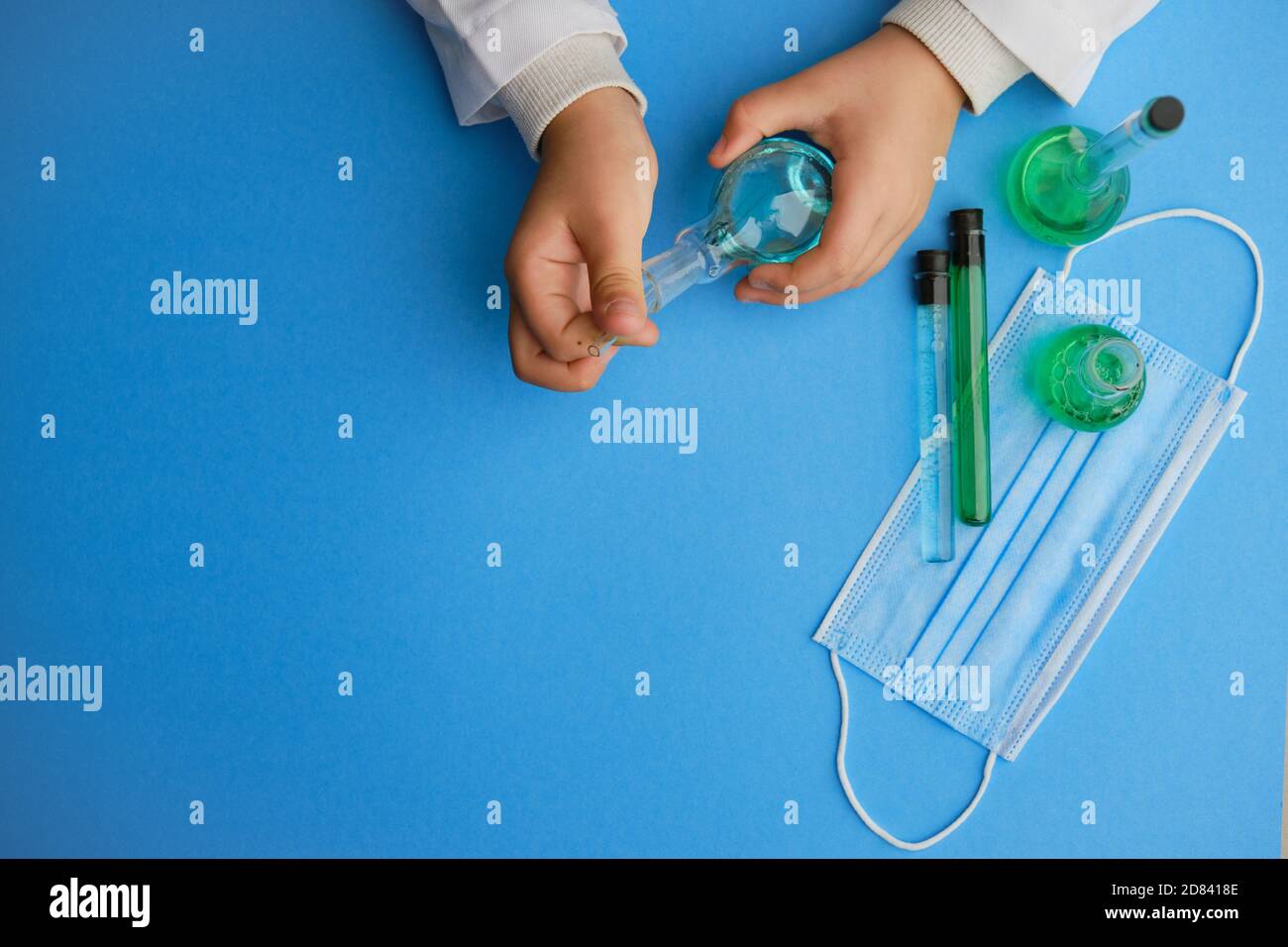 Matraccio per bambini e provetta in vetro in laboratorio, guardaroba. Chimica della soluzione. Soluzione antivirus. Liquido blu e verde Foto Stock